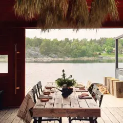 Vacker sommar restaurang Stockholm med dukat bord vid vattnet. Trädetaljer och grönska skapar en idyllisk atmosfär.
