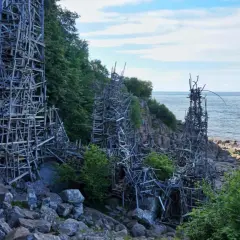 Lars Vilks Nimis, en skulptur av trä som reser sig mot himlen vid kusten.