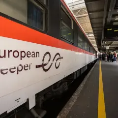 European Sleeper-tåget anländer till stationen, redo för nya nattåg. Folk väntar på perrongen.
