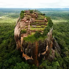 Imponerande ruiner på toppen av en klippa, som en fästning. En vy som påminner om Adams Peak, omgiven av frodig djungel.