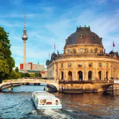 En båt på Spree-floden framför Bode-museet och Fernsehturm. En perfekt vy för din berlin reseguide.
