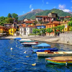 Färgstarka hus vid en sjö i Italien, med båtar i vattnet. Ett perfekt italienskt resmål för avkoppling.