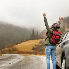 En person med ryggsäck vid en bil på en väg i Sverige. Vackert landskap med dimmiga berg. Bilsemester Sverige!
