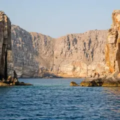 Majestätiska klippor reser sig ur det turkosa vattnet, en vy som påminner om en resa till Oman.