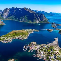 Vacker vy över Lofoten med berg, blått hav och små byar. En drömresa med tåg till Lofoten.