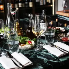 En elegant dukning med glas, flaskor och ostron på ett marmorbord. En härlig kväll på grus grus Odenplan.
