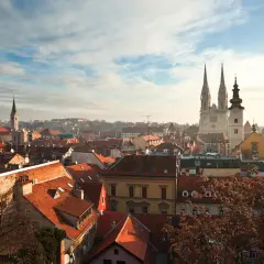 Vy över Zagreb, kroatiens huvudstad, med dess karakteristiska röda tak och imponerande katedral som reser sig mot en molnig himmel.