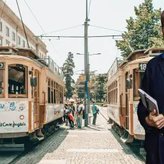 Man med anteckningsbok står framför spårvagnar i Portugal. Kanske är det här hans tåg till Portugal avgår.