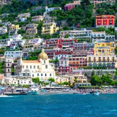 Färgstarka hus klättrar uppför en bergssluttning vid havet, en perfekt vy för en weekend i Italien.