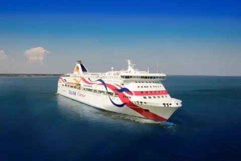 Stor färja, en Tallink-båt, glider fram på det blå havet under en klarblå himmel.