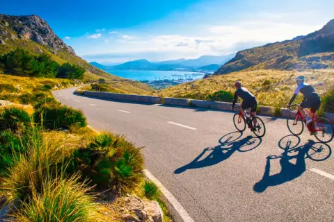 Två cyklister njuter av en solig dag med att cykla på Mallorca, med en fantastisk utsikt över havet och bergen.