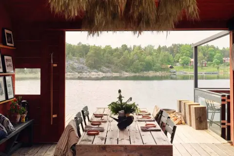 Vacker sommar restaurang Stockholm med dukat bord vid vattnet. Trädetaljer och grönska skapar en idyllisk atmosfär.
