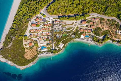 En vy över en ö med röda tak, gröna träd och turkost vatten. En plats som känns som en "mamma mia island" dröm.