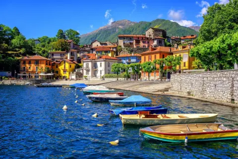 Färgstarka hus vid en sjö i Italien, med båtar i vattnet. Ett perfekt italienskt resmål för avkoppling.