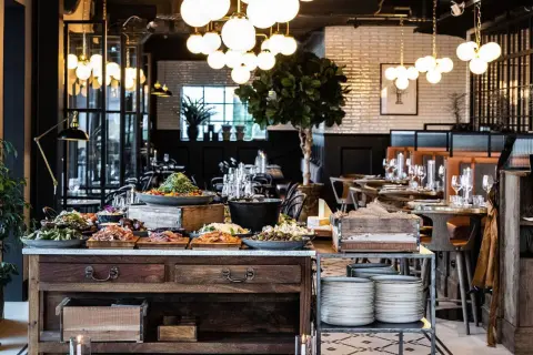 En generös buffé med mat och dryck på restaurang Kolmilan. Vackert dukade bord i bakgrunden.