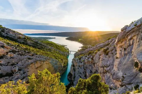 Solnedgång över Gorges du Verdon, med en turkos flod som slingrar sig mellan dramatiska klippor och frodig grönska.