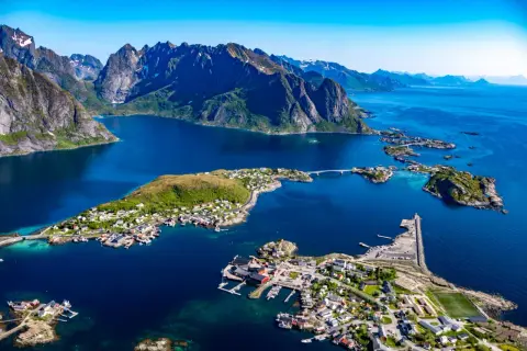 Vacker vy över Lofoten med berg, blått hav och små byar. En drömresa med tåg till Lofoten.