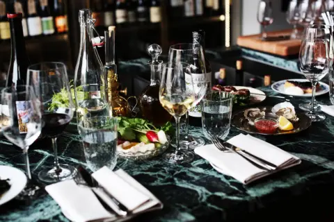 En elegant dukning med glas, flaskor och ostron på ett marmorbord. En härlig kväll på grus grus Odenplan.