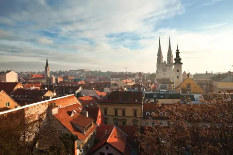 Vy över Zagreb, kroatiens huvudstad, med dess karakteristiska röda tak och imponerande katedral som reser sig mot en molnig himmel.