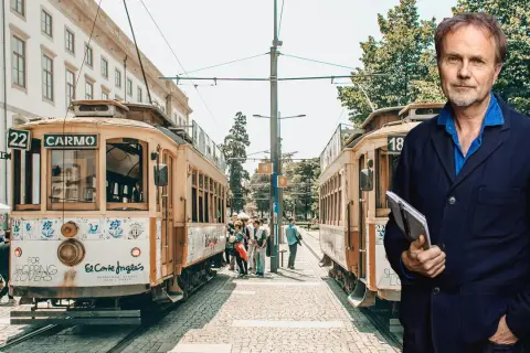 Man med anteckningsbok står framför spårvagnar i Portugal. Kanske är det här hans tåg till Portugal avgår.