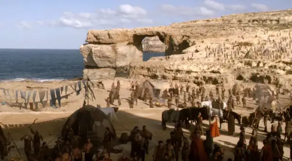En scen från Game of Thrones på Malta, med en stor folkmassa och tält vid havet under en klippformation.