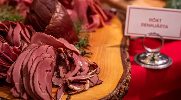 Rökt renkalv på ett rustikt träfat, en del av ett härligt tyrols julbord. Doften av jul sprider sig.