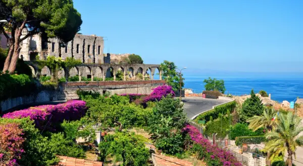Vacker vy över ruiner och bougainvillea vid havet, en dröm om Sardinien eller Sicilien.