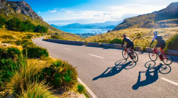 Två cyklister njuter av en solig dag med att cykla på Mallorca, med en fantastisk utsikt över havet och bergen.