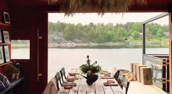 Vacker sommar restaurang Stockholm med dukat bord vid vattnet. Trädetaljer och grönska skapar en idyllisk atmosfär.