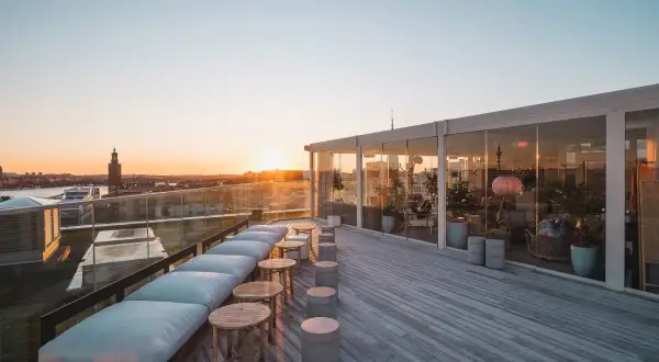 Takbar med utsikt över Stockholms silhuett vid solnedgången. En modern skyskrapa i Stockholm med sittplatser utomhus.