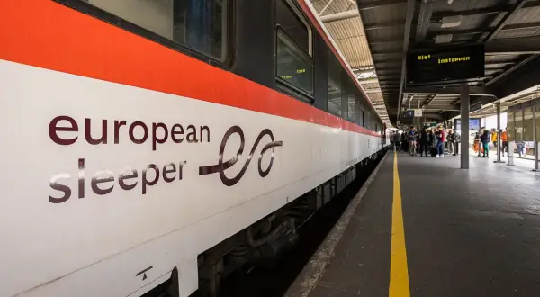 European Sleeper-tåget anländer till stationen, redo för nya nattåg. Folk väntar på perrongen.