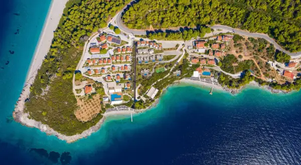En vy över en ö med röda tak, gröna träd och turkost vatten. En plats som känns som en "mamma mia island" dröm.