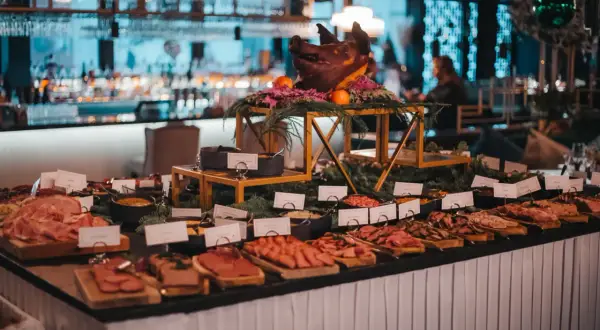 Ett dignande julbord med charkuterier, en dekorerad grisbuk och en bar i bakgrunden. En festlig Mister French julbord-upplevelse.
