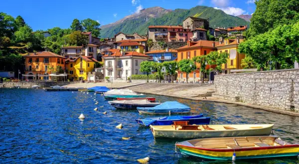 Färgstarka hus vid en sjö i Italien, med båtar i vattnet. Ett perfekt italienskt resmål för avkoppling.