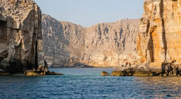 Majestätiska klippor reser sig ur det turkosa vattnet, en vy som påminner om en resa till Oman.
