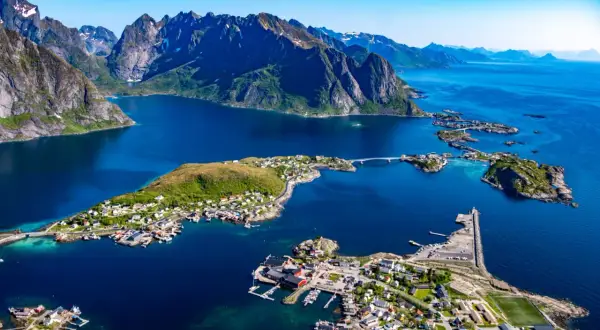 Vacker vy över Lofoten med berg, blått hav och små byar. En drömresa med tåg till Lofoten.