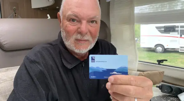 Man håller upp ett AutoPASS-kort för färjor, redo för bila i Norge.
