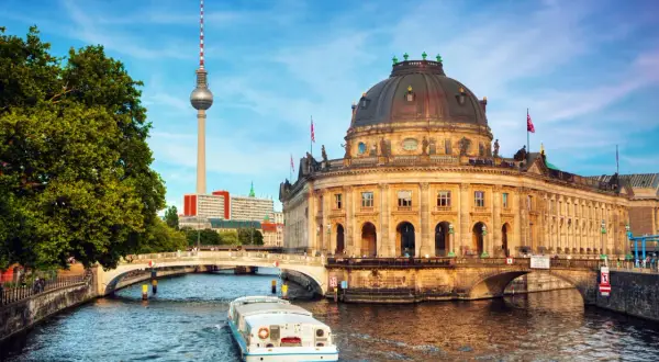 En båt på Spree-floden passerar Bode-museet och Fernsehturm, en av Berlins måsten.