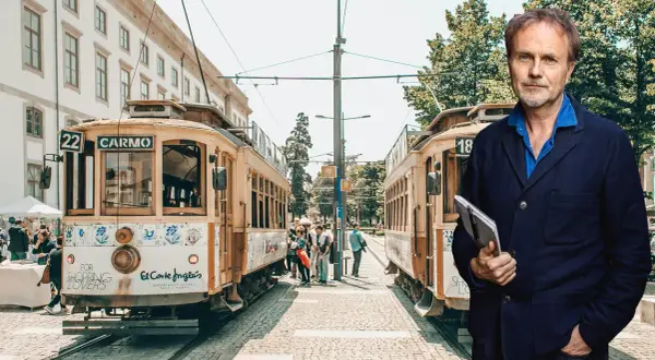 Man med anteckningsbok står framför spårvagnar i Portugal. Kanske är det här hans tåg till Portugal avgår.