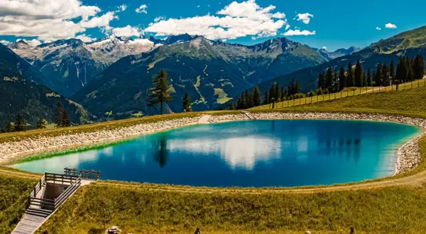 Vandra i Bad Gastein, en klarblå fjällsjö speglar majestätiska berg under en molnig himmel.