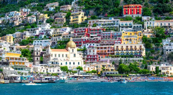 Färgstarka hus klättrar uppför en bergssluttning vid havet, en perfekt vy för en weekend i Italien.