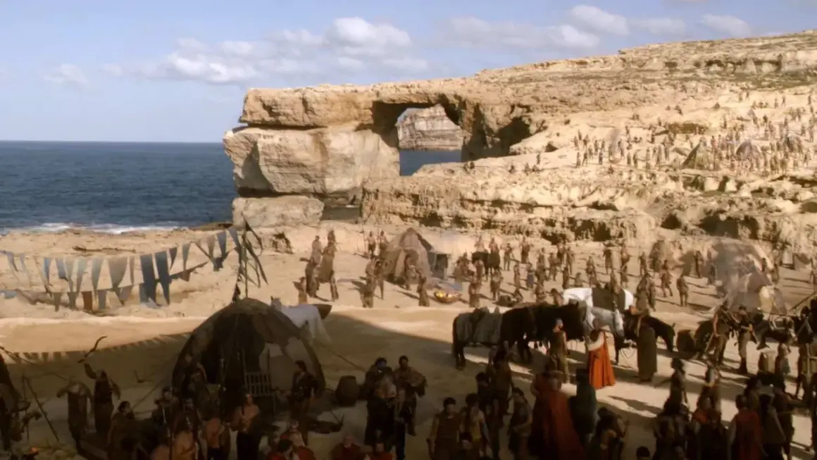 En scen från Game of Thrones på Malta, med en stor folkmassa och tält vid havet under en klippformation.