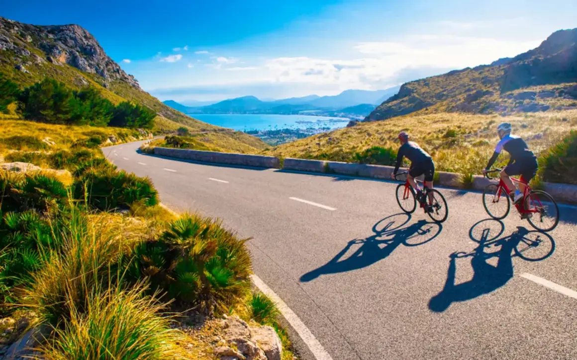 Två cyklister njuter av en solig dag med att cykla på Mallorca, med en fantastisk utsikt över havet och bergen.