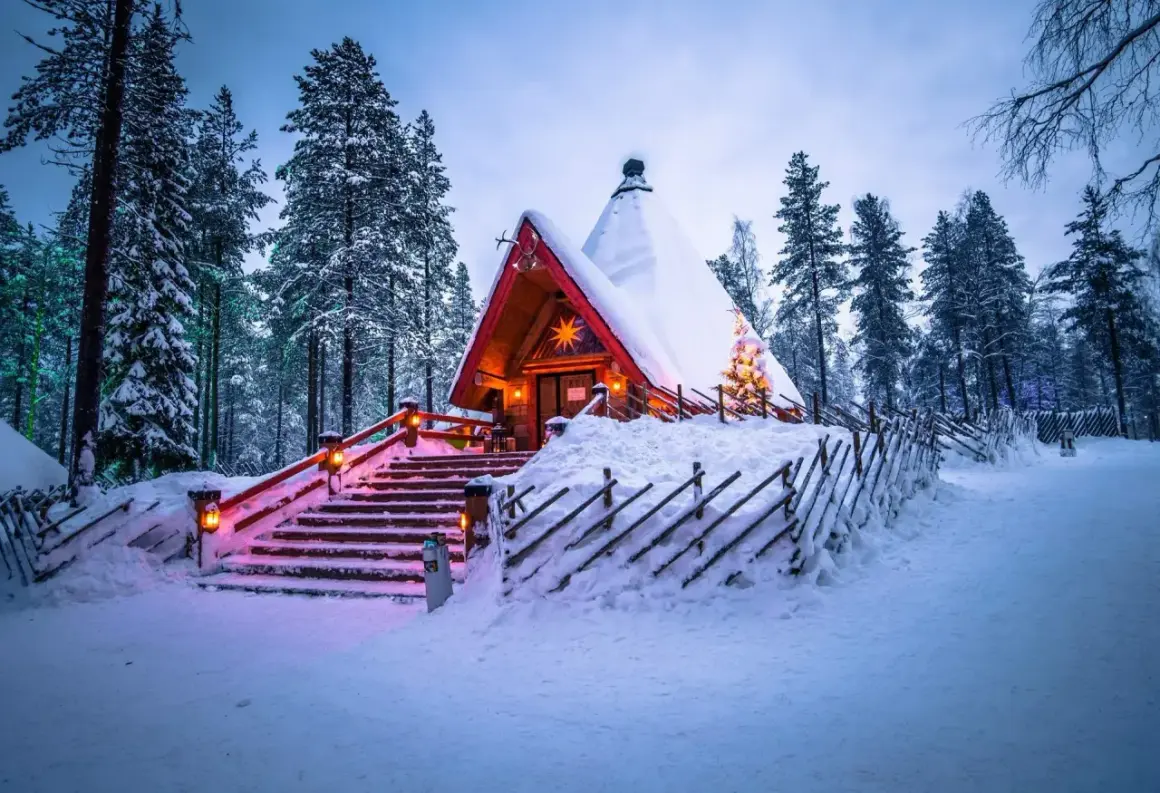 En snötäckt stuga i skogen, upplyst av julbelysning. En dröm för en solsemester vinter.