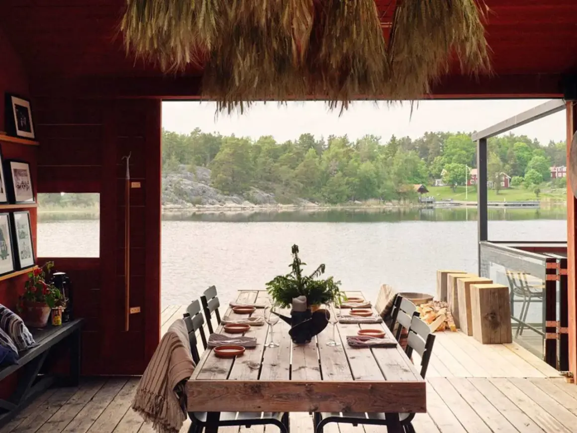 Vacker sommar restaurang Stockholm med dukat bord vid vattnet. Trädetaljer och grönska skapar en idyllisk atmosfär.