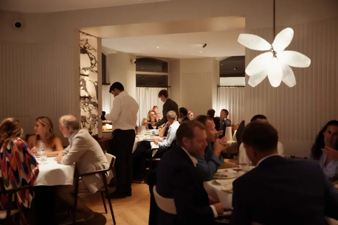 Gäster njuter av en middag på en elegant michelin restaurang i Karlstad. Servitörer serverar mat vid borden.