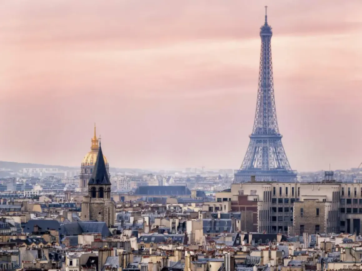 Eiffeltornet höjd över Paris takåsar i rosa skymningsljus. En gyllene kupol syns i bakgrunden.