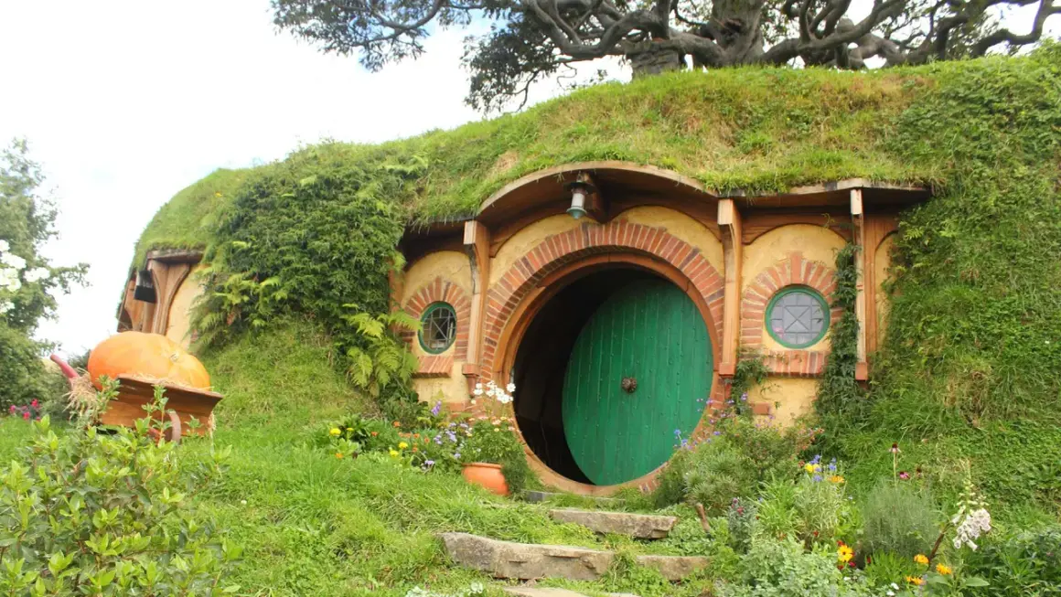 Här är en hobbit-lya, en plats där sagan om ringen spelades in. En stor pumpa ligger i en skottkärra.