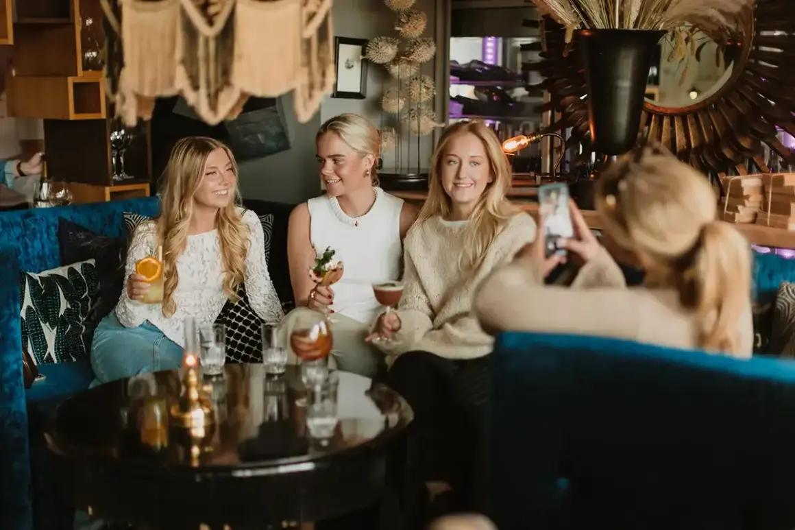 Tre unga kvinnor njuter av drinkar och sällskap under en mysig griffins brunch.