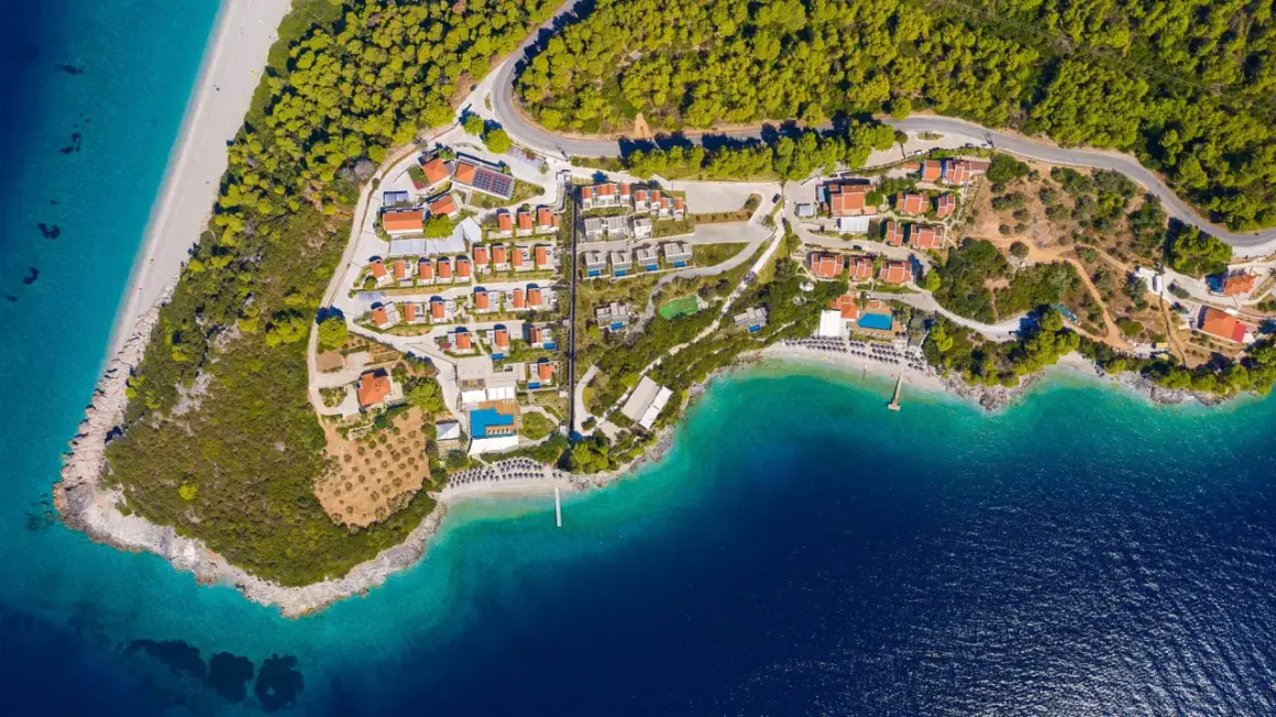 En vy över en ö med röda tak, gröna träd och turkost vatten. En plats som känns som en "mamma mia island" dröm.